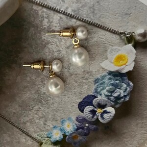 Peut inclure: Une paire de boucles d'oreilles en or avec des perles blanches. Les boucles d'oreilles ont un design simple et sont parfaites pour tous les jours.