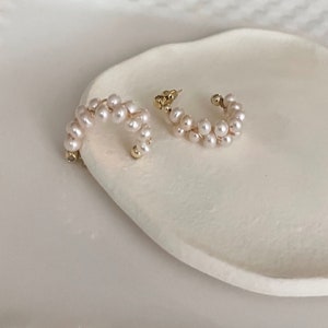 May include: A pair of gold hoop earrings with a double row of white pearls.