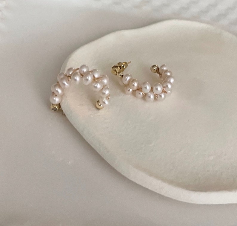 May include: A pair of gold hoop earrings with a double row of white pearls.