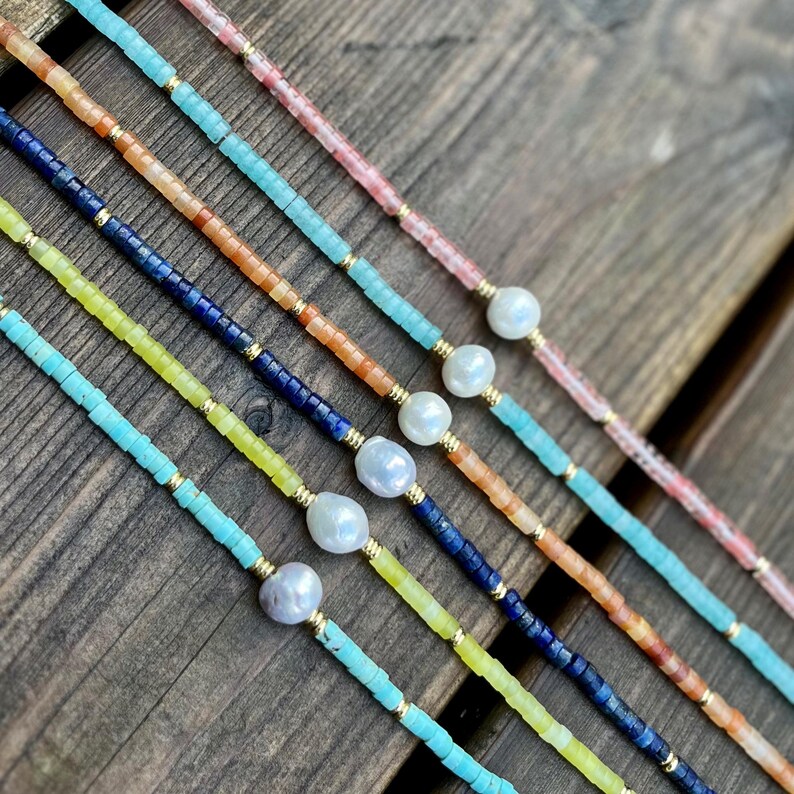 May include: Five beaded necklaces with a pearl accent. The necklaces are made with turquoise, yellow, blue, orange, and pink beads.
