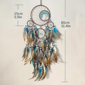 K&ouml;nnte beinhalten: Ein brauner und wei&szlig;er Traumf&auml;nger mit blauen und wei&szlig;en Perlen und Federn. Der Traumf&auml;nger ist 80 cm lang und 15 cm breit.