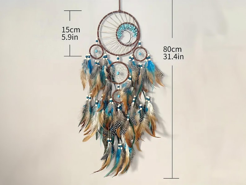 K&ouml;nnte beinhalten: Ein brauner und wei&szlig;er Traumf&auml;nger mit blauen und wei&szlig;en Perlen und Federn. Der Traumf&auml;nger ist 80 cm lang und 15 cm breit.