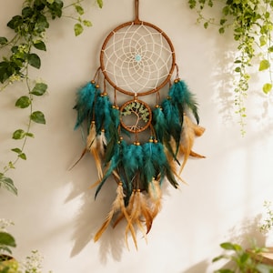 May include: A dream catcher featuring a large brown hoop with a white web and a central turquoise bead. Below, a smaller hoop contains a wire tree sculpture. The design is adorned with numerous teal and tan feathers attached with small gold beads.
