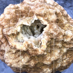 May include: A geode with a rough, textured exterior in shades of brown and tan. The center reveals a cavity filled with crystalline formations in off-white and pale green hues. The overall shape is rounded and irregular, showcasing natural geological beauty.