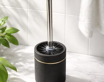 May include: A black toilet brush with a stainless steel handle and a gold accent band. The brush is cylindrical and sits on a white surface. The bristles are black.