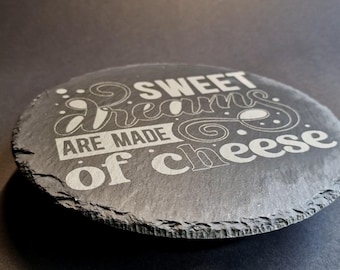 May include: A black slate cheese board with the text "Sweet dreams are made of cheese" engraved in white.