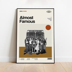 以下が含まれることがあります： 映画「Almost Famous」のフレーム入りポスター。ツアーバスの前でグループの人々が写っている白黒写真が特徴です。ポスターはクリーム色の背景で、映画のタイトルが大きな黒い文字で書かれています。
