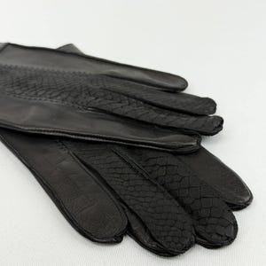 Peut inclure: Paire de gants en cuir noir avec un motif peau de serpent sur le dos de la main et les doigts. Les gants sont en cuir souple et semblent neufs. Les gants sont probablement pour le froid ou la mode.