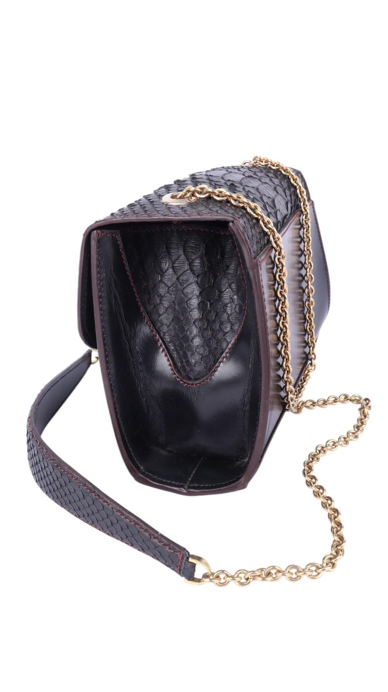 May include: Black leather handbag with a snakeskin texture. It has a gold chain strap and a matching snakeskin strap. The interior is black with red stitching. The bag is open, showing the inside.