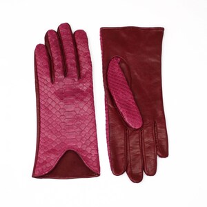 Op de afbeelding: Een paar bordeauxrode leren handschoenen. Eén handschoen heeft een slangenhuidpatroon op de achterkant van de hand en de andere handschoen is effen bordeauxrood.