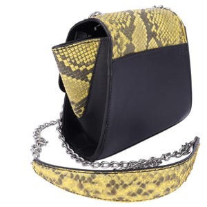 May include: Black and yellow snakeskin-patterned crossbody bag with a silver chain strap. The bag features a flap closure and a contrasting black leather body. The snakeskin pattern is primarily yellow and brown.