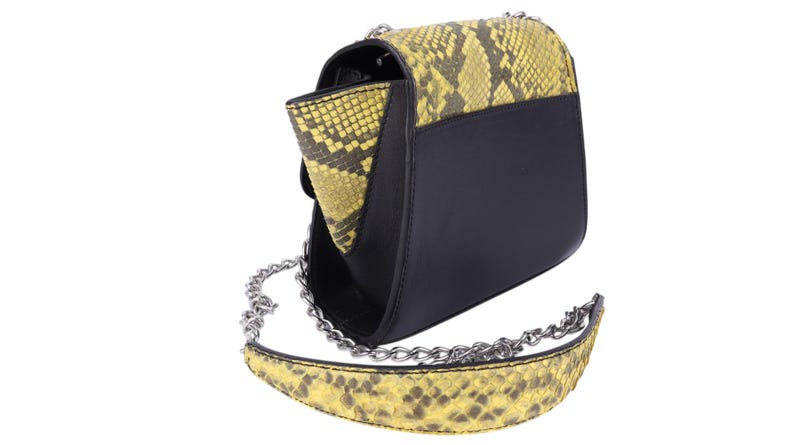 May include: Black and yellow snakeskin-patterned crossbody bag with a silver chain strap. The bag features a flap closure and a contrasting black leather body. The snakeskin pattern is primarily yellow and brown.