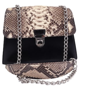 Pode incluir: Uma bolsa preta com padrão de pele de cobra e alça de corrente prateada. A bolsa apresenta um fecho de aba com um fecho prateado. O padrão de pele de cobra é uma mistura de castanho, bege e creme.