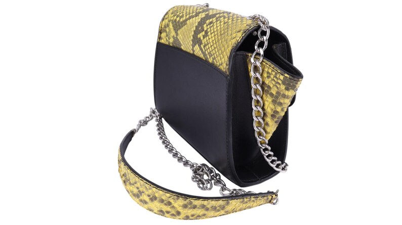 May include: Black and yellow snakeskin-patterned shoulder bag with a silver chain strap. The bag has a black body and a flap with a snakeskin design. The strap is a silver chain with a snakeskin-patterned shoulder pad.