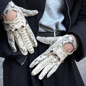 Peut inclure: Une paire de gants crème avec un motif peau de serpent. Les gants ont des détails découpés sur les jointures et des bracelets de poignet avec une fermeture à bouton. Les gants sont en matière texturée.