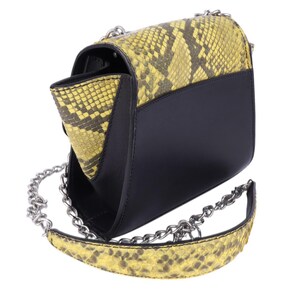 May include: Black and yellow snakeskin-patterned shoulder bag with a silver chain strap. The bag has a flap closure and a black body. The snakeskin pattern is yellow and brown.