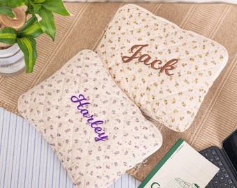 May include: Two quilted pillows with floral patterns and embroidered names. One pillow has the name "Jack" in brown thread, and the other has "Harley" in purple thread. The pillows are cream-colored with small yellow and purple flowers.