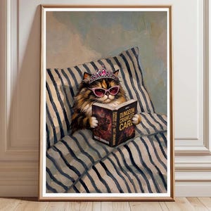 Puede incluir: Un gato calicó esponjoso con una tiara rosa y gafas de sol de ojo de gato rosas, leyendo un libro titulado Dungeon Crawler Carl. El gato descansa sobre una almohada con un patrón de rayas verticales azules y blancas en este cuadro.