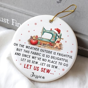 Könnte beinhalten: Runder weißer Weihnachtsbaumschmuck aus Keramik mit Nähmaschine, Tomate, Lebkuchenmann und Text. Der Text lautet: "Oh, das Wetter draußen ist schrecklich, aber dieser Stoff ist so entzückend..." mit einem Namen darunter.