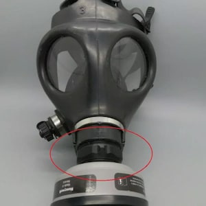 Puede incluir: Máscara de gas negra con una visera transparente y un filtro negro unido a la parte inferior. El filtro tiene una etiqueta blanca que dice "Honeywell" y "Made in USA".