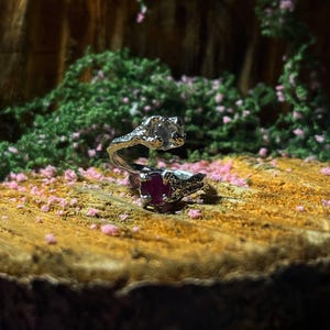 May include: A white ceramic mug with a black handle and the text "But First, Coffee" in a bold, black font. The mug is set against a blurred background, suggesting a cozy setting.