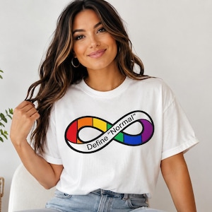 May include: A white short-sleeved t-shirt featuring a black-outlined infinity symbol graphic. The symbol is segmented into rainbow-coloured sections and contains the black text "Define "Normal"" printed across the centre of the design.
