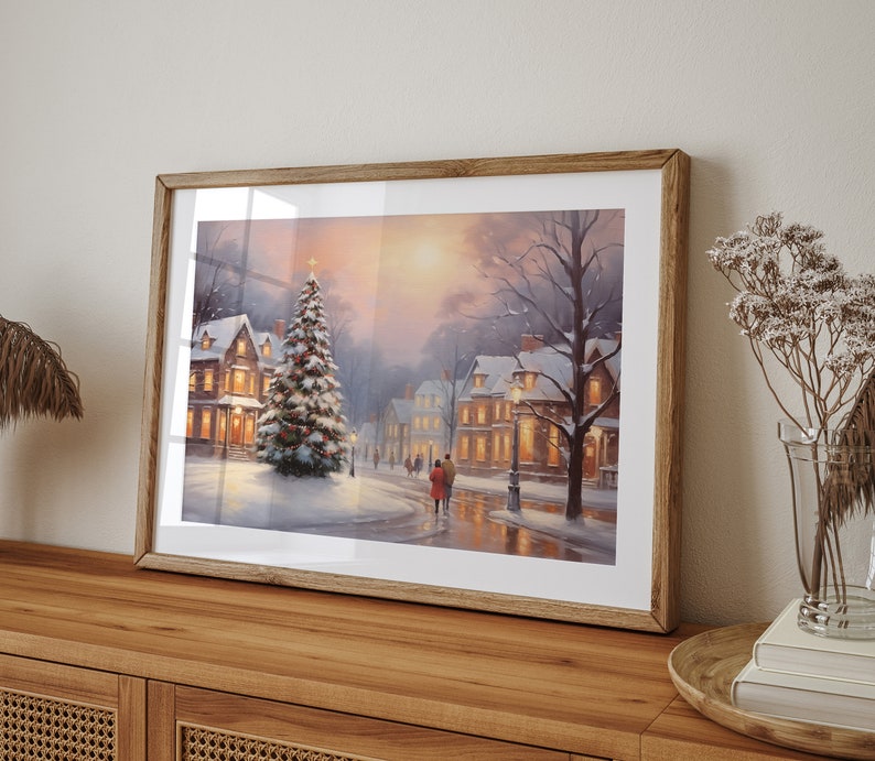 Puede incluir: Una pintura enmarcada de una escena de invierno en un pueblo cubierto de nieve, con un &aacute;rbol de Navidad iluminado en primer plano. La pintura presenta a una pareja caminando por la calle, casas con ventanas iluminadas y una farola.