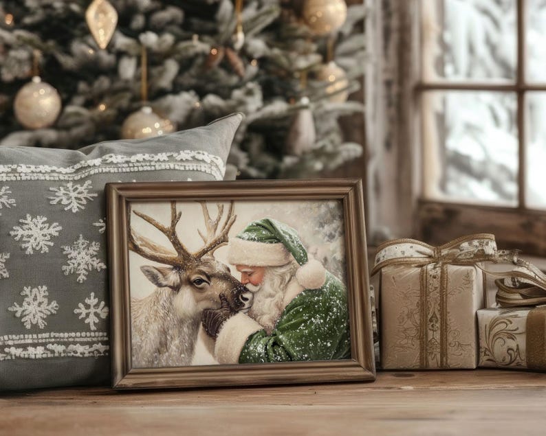 May include: A framed Christmas print depicts Santa Claus in a green suit and hat, nuzzling a reindeer. The print is in a brown frame, resting on a wooden surface. A gray pillow with snowflake embroidery and wrapped gifts are in the background.