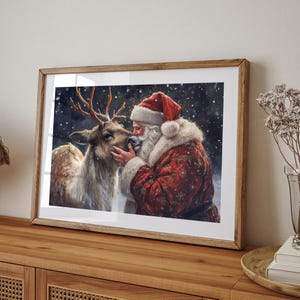 May include: A framed painting of Santa Claus with a white beard and red hat, kissing a reindeer on the nose. The background is a snowy forest scene.