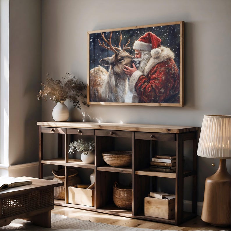 May include: A painting of Santa Claus kissing a reindeer on the nose. The painting is set against a snowy background with a wooden frame.