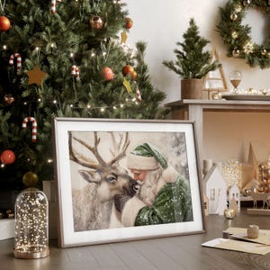 May include: A framed print of Santa Claus and a reindeer, with a green and white color scheme. The image is set against a Christmas tree background with ornaments and lights. The frame is a light brown color.