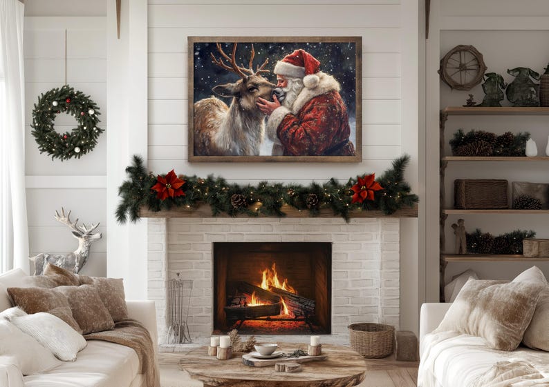 May include: A painting of Santa Claus with a white beard and red suit, kissing a brown and white deer on the nose. The painting is framed in wood and has a white background with snowflakes. The painting is hanging on a white wall above a fireplace with a garland of greenery and red poinsettias.
