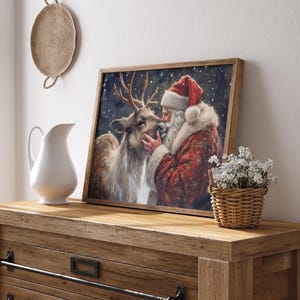 May include: A framed painting of Santa Claus with a reindeer. Santa is wearing a red suit with white trim and a red hat. The reindeer is brown with antlers. The background is a snowy night scene.