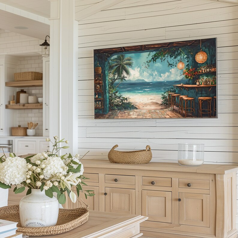 May include: A light wood cabinet with four doors and a woven basket on top. The cabinet is against a white wood wall with a painting of a tropical bar scene above it. The painting features a blue ocean, palm trees, and a bar with stools.