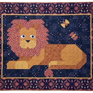 May include: A patchwork quilt featuring a lion with a red mane and a brown body, lying down on a dark blue background with gold stars and butterflies. The quilt has a red and gold border with a floral pattern.