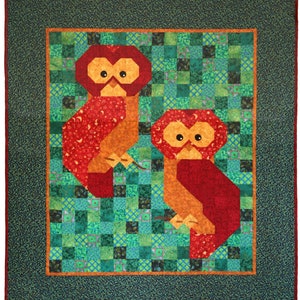 May include: Two red and orange owls with stars and moons on their bodies are sitting on a green and blue patchwork quilt.