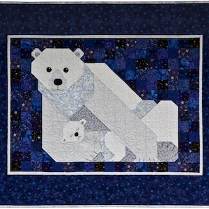 May include: A handmade quilt depicting a polar bear and cub. The bears are white with black features, set against a patchwork of blue fabrics with star patterns. The quilt has a dark blue border with small white stars.