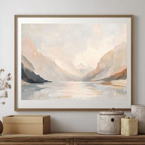 Pode incluir: Uma pintura abstrata emoldurada que representa uma cordilheira refletida em um lago tranquilo. A pintura está em tons de marrom, bege e branco, com uma sensação suave e de sonho.