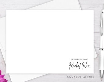 May include: A white flat card with the text "FROM THE DESK OF Rachel Roe" and "5.5" x 4.25" FLAT CARD" printed on it. The card is lying on a white wooden surface with a white pen and pink flowers.