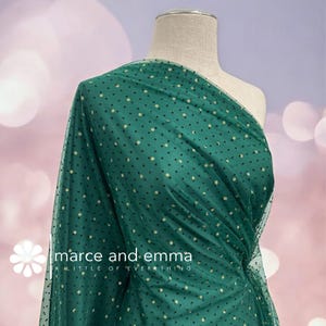 May include: Emerald green tulle fabric with small black and gold polka dots, draped over a mannequin. The fabric is semi-sheer and has a delicate texture. The text "marce and emma A LITTLE OF EVERYTHING" is visible.