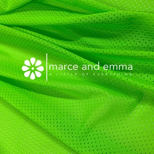 May include: Bright green mesh fabric with a small, white flower and the text "marce and emma a little of everything" printed on it.