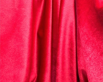 May include: A close-up of a light red fabric with a smooth texture. The fabric is folded and draped, creating soft folds and curves.