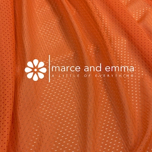May include: Orange mesh fabric with a small white flower logo that says "marce and emma a little of everything".