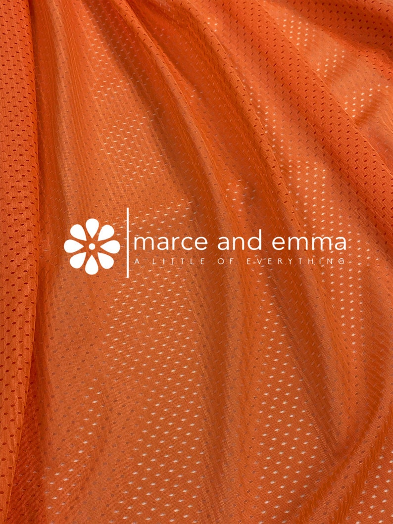 May include: Orange mesh fabric with a small white flower logo that says "marce and emma a little of everything".