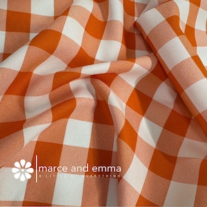 May include: Orange and white checkered fabric with the text "marce and emma a little of everything" in the bottom left corner.