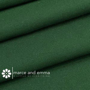 May include: Close-up of a deep green fabric with a subtle diagonal weave. The fabric is folded in thirds, showing the texture and color.