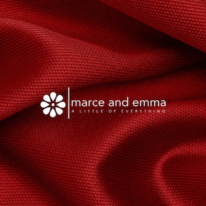 May include: A deep red fabric with a textured, woven surface featuring a white logo that displays a stylized flower icon next to the text marce and emma and the tagline A LITTLE OF EVERYTHING positioned below the brand name in a clean font.