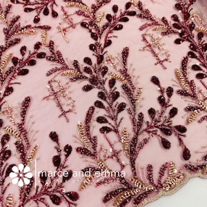 May include: Burgundy and gold beaded floral lace fabric. The lace features a delicate floral pattern with small beads and sequins.