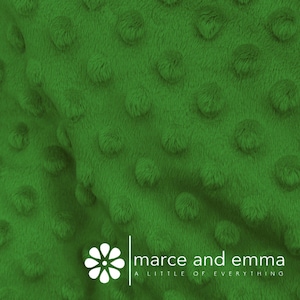 May include: Close-up of a green minky fabric with a textured, dotted pattern. The fabric is soft and plush, perfect for blankets, pillows, and other crafts.