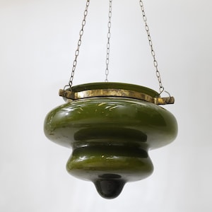 Puede incluir: Lámpara colgante de vidrio verde oliva con detalles de latón y cadena para colgar. La lámpara tiene un diseño redondeado y en capas con una base oscura. Un artículo de decoración del hogar de estilo vintage.